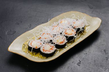 Süslü tabakta çıtır pirinç eriştesi, somon ve krem peynirle kaplı gurme suşi ruloları. Yüksek kalite fotoğraf