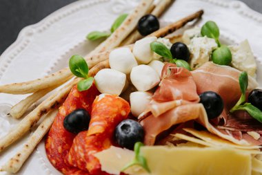 Pişmiş et, peynir, zeytin, ekmek çubuğu ve taze otlarla İtalyan antipasto tabağı. Yüksek kalite fotoğraf