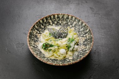 Krem soslu gurme makarna, ıspanak, yenilebilir zarif dekorasyon - nefis bir yemek tabağı. Yüksek kalite fotoğraf