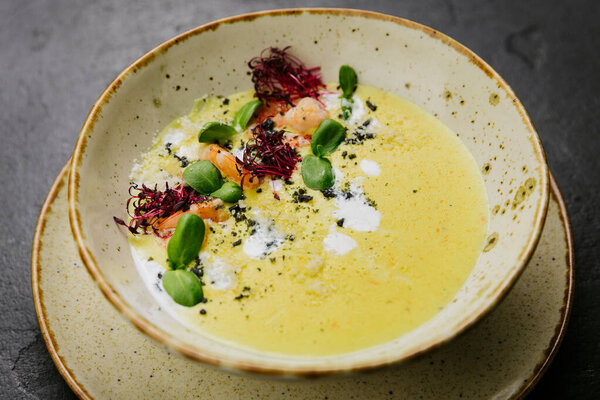 Сливочный изысканный суп с креветками, микрозеленью и художественным оформлением - элегантное изысканное обеденное блюдо. Высокое качество фото