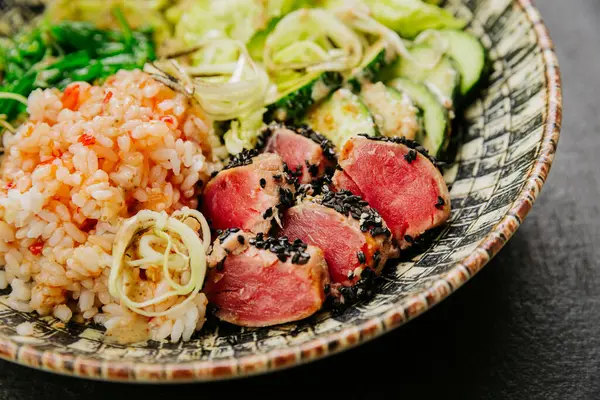 stock image Healthy poke bowl with seared tuna, rice, seaweed salad, and fresh vegetables - vibrant and nutritious. High quality photo