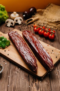 Tahtaya tütsülenmiş salam çubukları. Şarküteri tahtaları ve gurme sunumları için mükemmel. Yüksek kalite fotoğraf