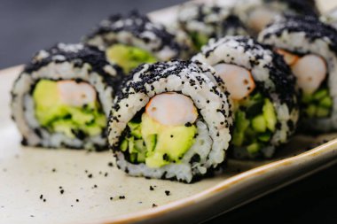 Suşi karides, avokado ve siyah havyarla yapılıyor. Japon mutfağı ve yemek tasarımı için mükemmel. Yüksek kalite fotoğraf