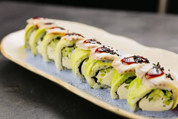 stock image Eel sushi roll with creamy filling, topped with savory sauce and sesame seeds on a stylish plate. High quality photo