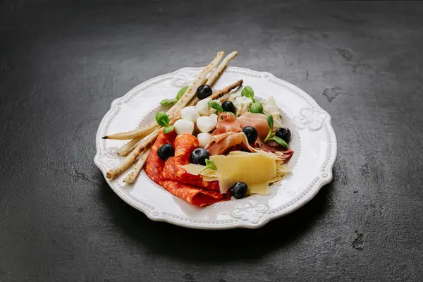 stock image Italian antipasto platter with cured meats, cheese, olives, breadsticks, and fresh herbs . High quality photo