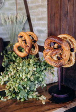 Traditional Bavarian pretzels displayed on stands with fresh hops, Oktoberfest and German cuisine. High quality photo