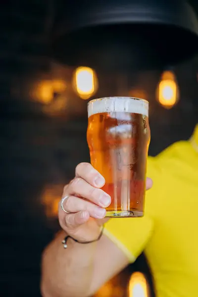 stock image Close-up of person holding glass of beer with blurred pub background. Beer-related content. High quality photo