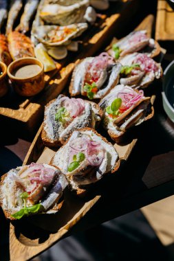 Open-faced sandwiches with herring, cream cheese, pickled onions, and herbs on rye bread. High quality photo clipart