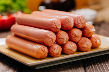 Tabakta bir yığın sosis, barbekü, ızgara ya da hızlı yemek için ideal mutfak ortamında sergileniyor. Yüksek kalite fotoğraf