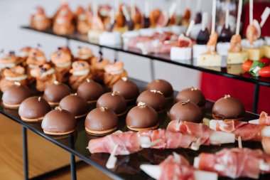 Gurme çikolatalı tatlılar ve lezzetli prosciutto aperatifleri etkinlik ya da yemek servisi için sergileniyor. Yüksek kalite fotoğraf