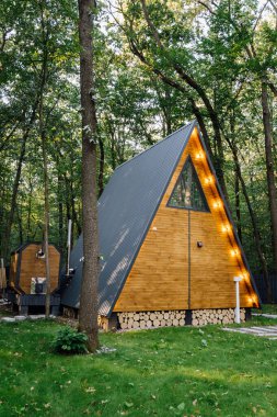 Orman ortamında parlayan sicim ışıkları olan modern A-frame kamaraları, barışçıl bir geri çekilme için ideal. Yüksek kalite fotoğraf