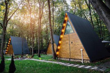 Ormanda, güneş ışığı ve açık hava oturma alanı olan ahşap kulübeler. Yüksek kalite fotoğraf