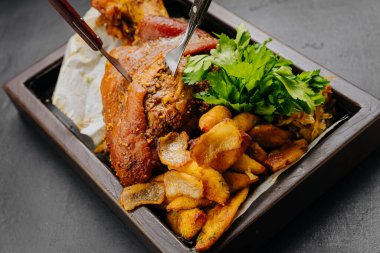 Roasted pork knuckle with potatoes and fresh herbs on wooden tray, stock food photography. High quality photo clipart