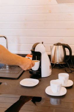 Man preparing morning coffee using a coffee machine, creating a cozy atmosphere at home. High quality photo clipart