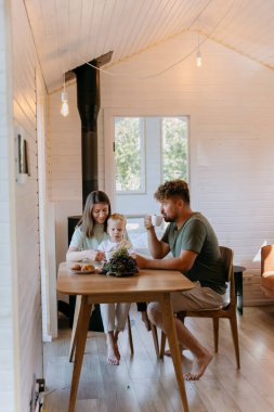 Evde taze kruvasanlar, üzümler ve kahveyle birlikte aile kahvaltısı. Birlikte güzel vakit geçiriyoruz. Yüksek kalite fotoğraf