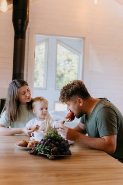 Father and son enjoying breakfast together with fresh fruit and pastries, creating family moment. High quality photo clipart