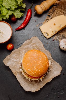 Kraft kağıdındaki hamburgerin tepeden tırnağa görüntüsü içinde taze malzemeler, yemek menüleri ve pazarlama kampanyaları var. Yüksek kalite fotoğraf