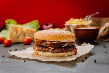 Eritilmiş peynirli duble çizburger, turşu ve susamlı ekmek üzerine barbekü sosu. Yemek fotoğrafçılığı. Yüksek kalite fotoğraf