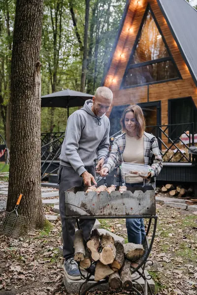 Çift birlikte ızgara yapıyor, orman ortamında odun ve doğa ile barbekü yapıyor. Yüksek kalite fotoğraf