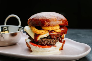 Soğan halkası, gurme burgerin üstüne patates kızartması. Yemek severler için mükemmel bir yemek. Yüksek kalite fotoğraf