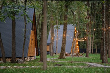 Ormanda, güneş ışığı ve açık hava oturma alanı olan ahşap kulübeler. Yüksek kalite fotoğraf