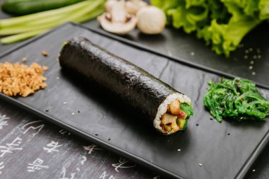 Gimbap roll with fresh vegetables, mushrooms and chicken, served with seaweed salad and fried onions. High quality photo clipart