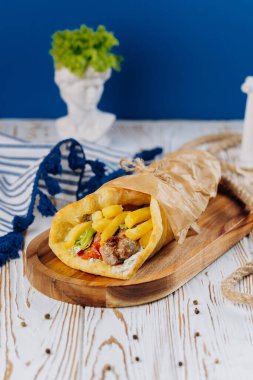 Juicy gyro wrap with fries, vegetables, and sauce, perfect for Mediterranean street food experience. High quality photo clipart