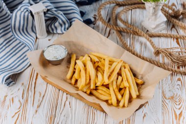 Golden French fries with a side of creamy dip, perfect for snack lovers. High quality photo clipart