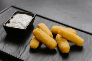 Pürüzsüz, siyah bir tabakta servis edilen kremalı peynirli çubuklar. Mükemmel aperatif. Yüksek kalite fotoğraf