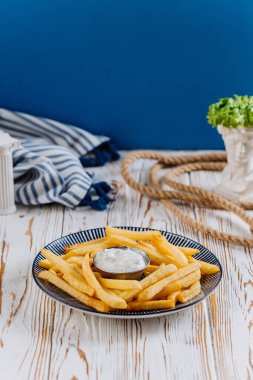 Golden French fries with a side of creamy dip, perfect for snack lovers. High quality photo clipart