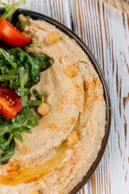 Taze yeşillik, vişneli domates ve sağlıklı yemek için nohut ile yakın plan kremalı humus. Yüksek kalite fotoğraf