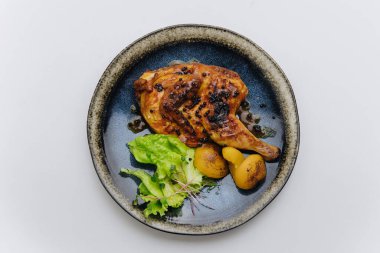 Karabiberli sulu kızarmış tavuk, ızgara patates ve taze yeşillikler, zarif bir tabakta. Yüksek kalite fotoğraf