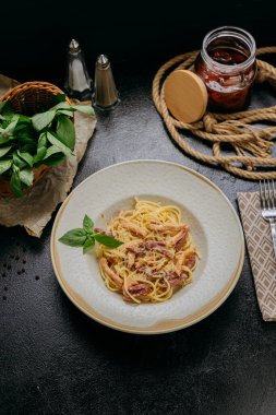 Parmesan peynirli, fesleğenli ve çıtır pastırmalı klasik carbonara makarnası. Yüksek kalite fotoğraf