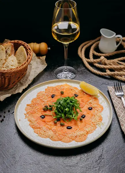 Arugula, kapari, parmesan ve limon dilimli somon carpaccio, beyaz şarapla servis edilir. Yüksek kalite fotoğraf