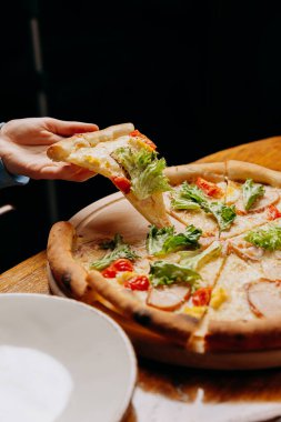 Marul, domates ve peynirle kaplı taze bir dilim pizza alıyorum. Yüksek kalite fotoğraf