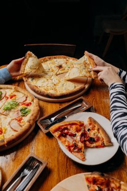 Sıcak bir yemek deneyimi için arkadaşlar arasında paylaşılan taze malzemeli çeşitli pizzalar. Yüksek kalite fotoğraf
