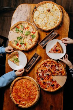Kırsal bir masada servis edilen çeşitli lezzetli pizzalar, sıradan bir yemekte paylaşmak için mükemmel. Yüksek kalite fotoğraf