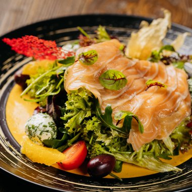 Tütsülenmiş somon, canlı yeşiller ve masada sanatsal süslemeler olan bir gurme salatasının en üst görüntüsü. Yüksek kalite fotoğraf