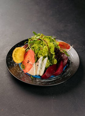 Yeşillikli taze gurme salatası, mavi peynir, narenciye ve siyah bir tabakta kurutulmuş meyve. Yüksek kalite fotoğraf