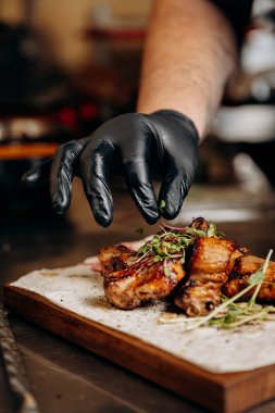 Chef garnishing grilled ribs with fresh greens, adding the final touch to a savory dish. High quality photo clipart