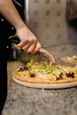 Şef taze sebzeli pizzayı granit tezgahta pizza dilimliyor. Yüksek kalite fotoğraf