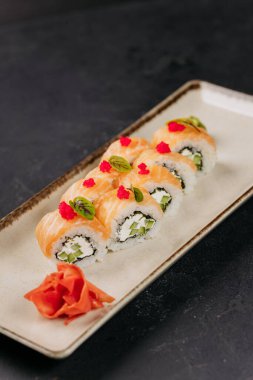 Suşi dürümleri, somon, krem peynir ve salatalık, wasabi ve roe ile süslenmiş. Yüksek kalite fotoğraf