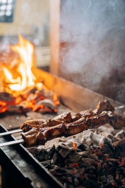 Kızarmış et şişleri mangal kömürü alevlerinde kızarıyor, barbekü mükemmelliğinin özünü yakalıyor. Yüksek kalite fotoğraf