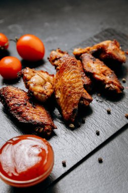 Juicy grilled chicken wings served with fresh tomatoes and spices, perfect for a delicious meal. High quality photo clipart