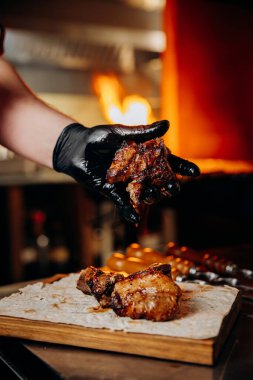 Chef holding grilled meat piece over flatbread, capturing the essence of flame-grilled flavor. High quality photo clipart