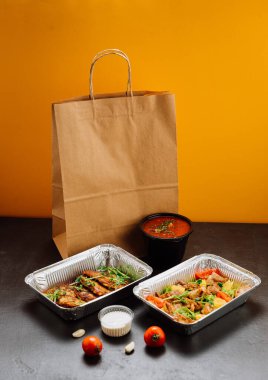 Tepsiler dolusu lezzetli yemek, sos kapları ve kese kağıdıyla birlikte yiyecek teslimatı. Yüksek kalite fotoğraf