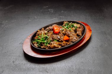 Soğanlı ve taze yeşillikli ızgara sığır ciğeri sıcak tabakta servis edilir, sağlıklı bir yemek için mükemmeldir. Yüksek kalite fotoğraf