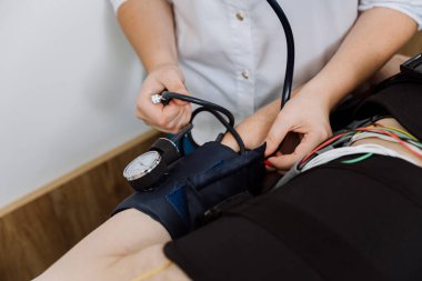 Healthcare worker checking blood pressure of a patient during a diagnostic procedure. High quality photo clipart