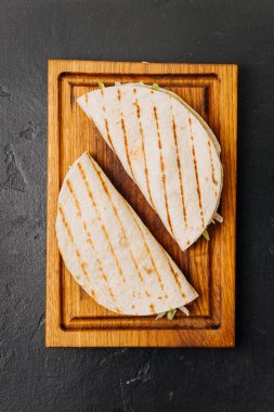 Izgara tortilla, ahşap bir tahtanın üzerinde taze sebzelerle sarılı, hızlı ve lezzetli bir yemek için. Yüksek kalite fotoğraf