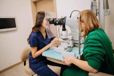 Optometrist conducting an eye examination using a slit lamp in a modern clinic setting. High quality photo clipart